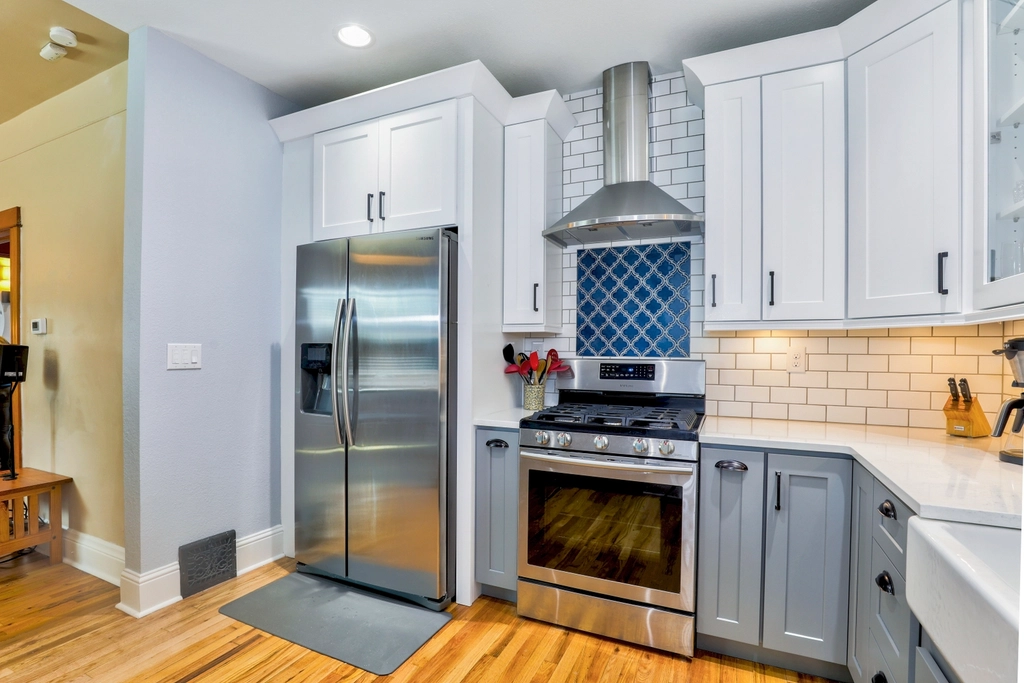 Kitchen with gray lower cabinets and a stainless range hood