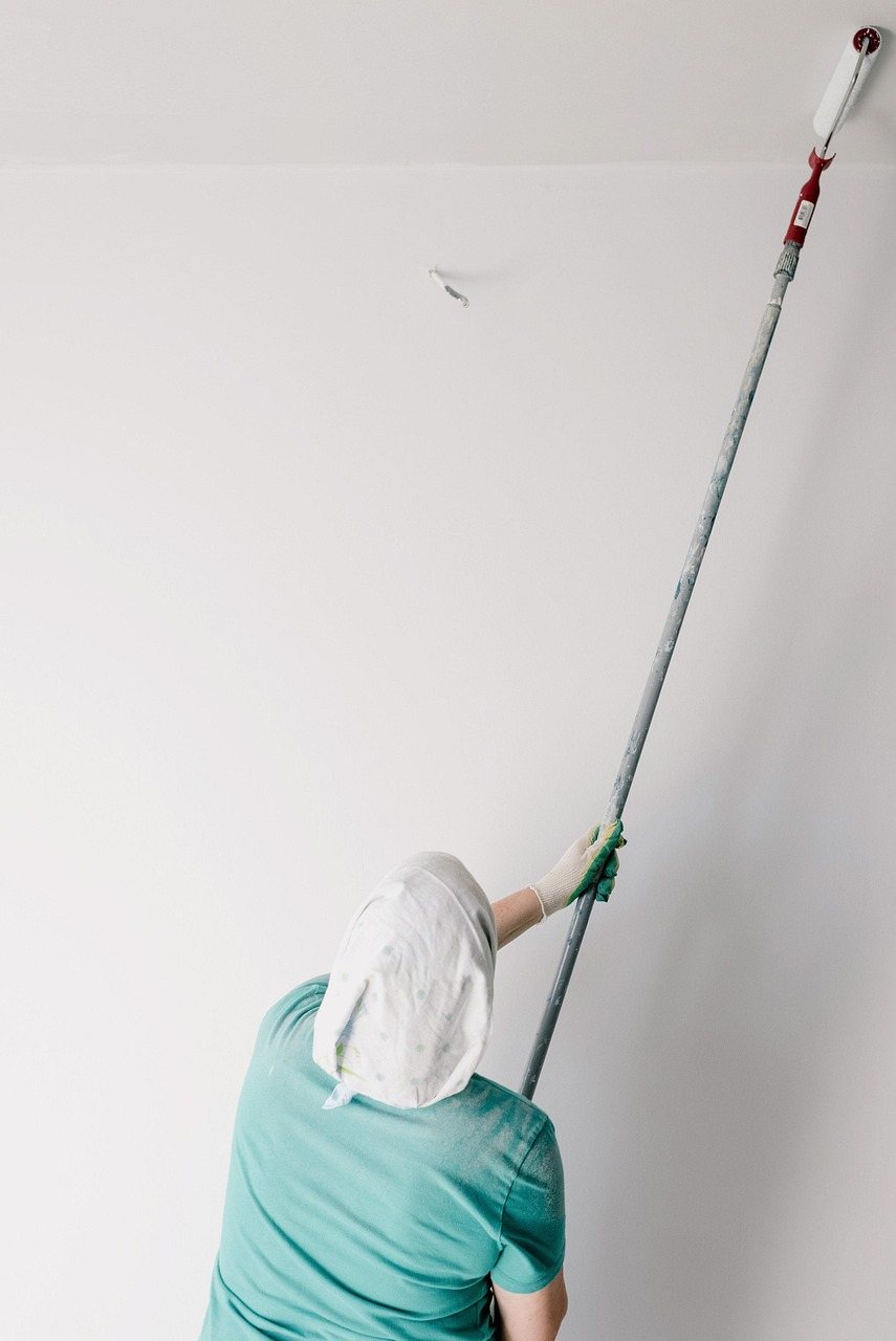 Painter rolling a ceiling-height wall with an extension pole