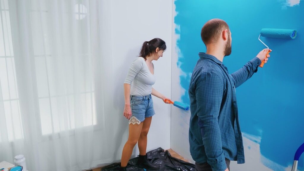 Two painters rolling a wall in a room