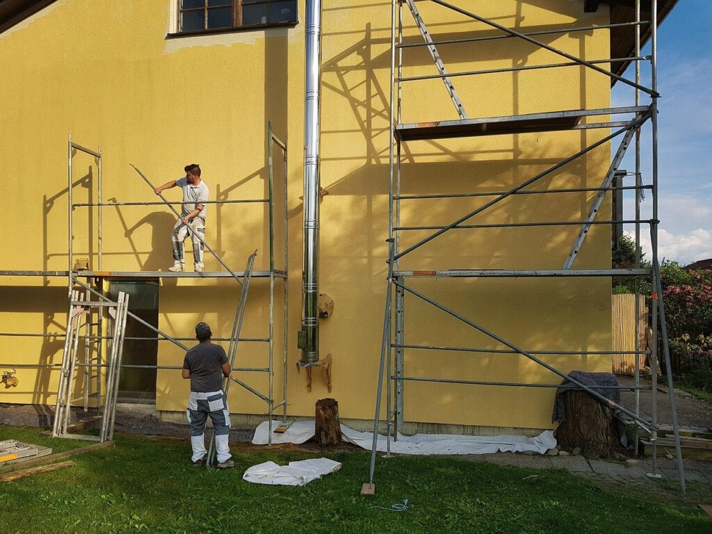 Painters working from scaffolding on a house exterior